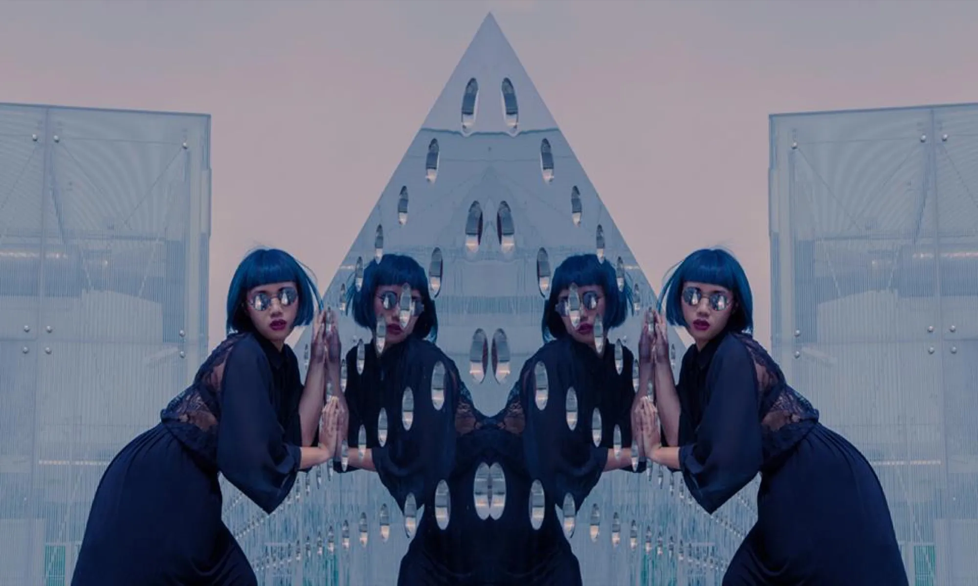 Mirrored composition: twin figures with blue bob haircuts praying before a pyramid-shaped building
