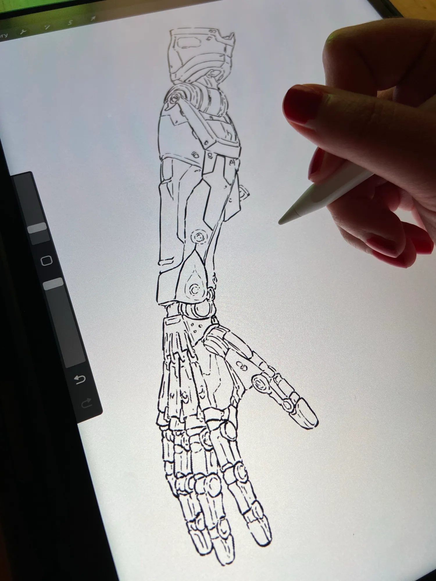 A mechanical arm being inked on the iPad, stylus hovering over the linework